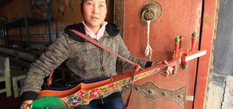 A young blind girl playing traditional tibet instrument