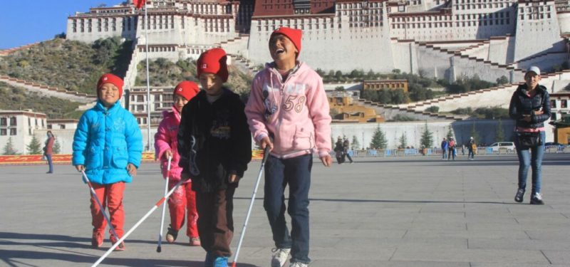 Blind children walking on the street of Tibet using white cane