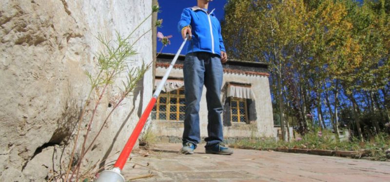 Picture take from floor level of a blind kid walking with cane